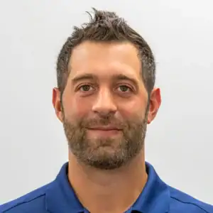 Professional man in blue polo shirt smiling, headshot for financial services website.