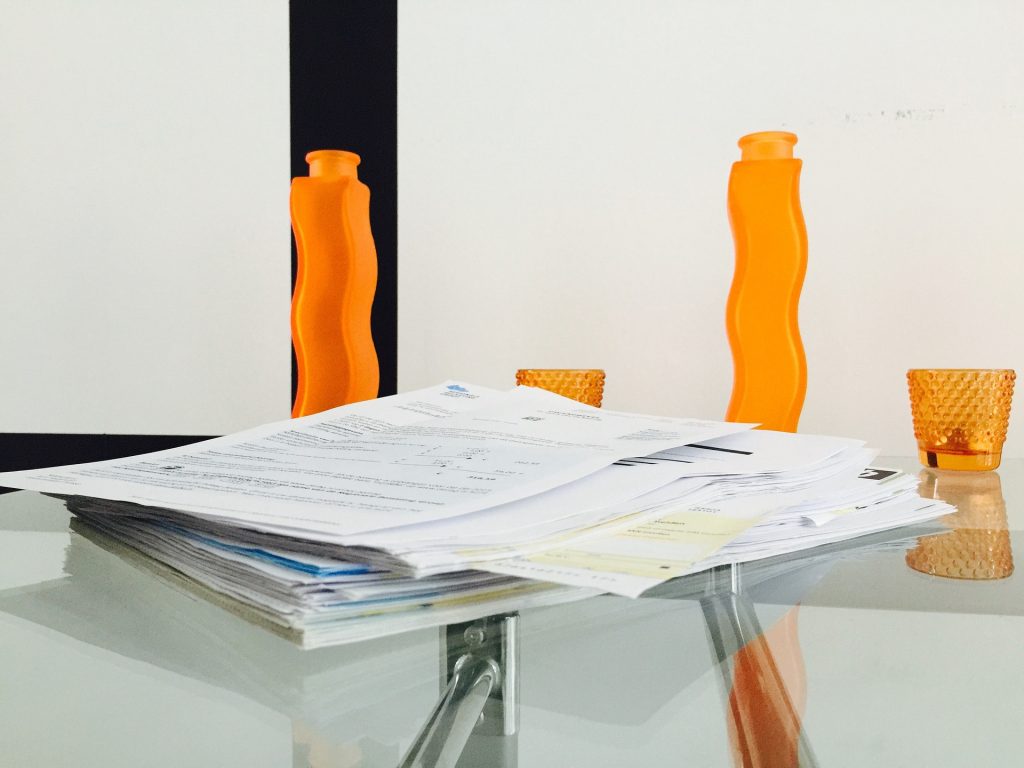 A pile of invoices on a glass desk