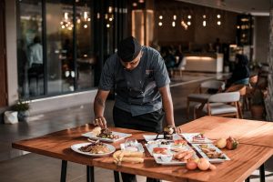 A chef arranging food on a table at his restaurant business