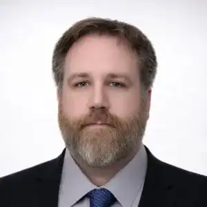 Headshot of a professional man with a beard in a suit and tie, representing United Capital Source's.