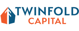 TwinFold Capital Logo - The image is set in a small wholesale distribution department delivering end-to-end fulfillment. It features a proud business owner and a dedicated, helpful team reviewing inventory on tablets in a well-organized warehouse. Natural light illuminates the space filled with shelves of boxed products and active forklifts, conveying a sense of productivity and growth, reflective of the hard work and operational efficiency that clients create to drive small business success.