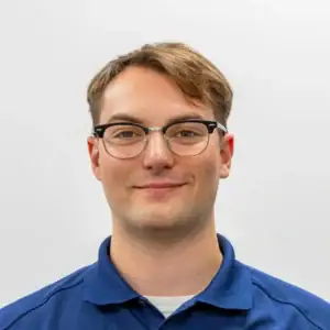 Flexible business professional wearing glasses and a blue polo shirt, smiling confidently against a.