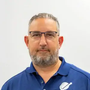 Professional man in blue polo shirt with glasses, facing camera.
