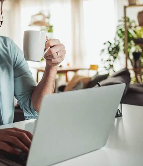 Modern office workspace with a person using a laptop and holding a coffee mug.