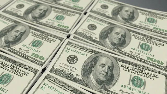 Close-up of rows of U.S. hundred-dollar bills spread across a table, a nod to who qualifies for the employee retention credit