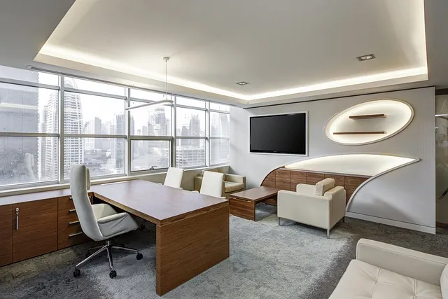 Executive office with a wood desk, white leather chairs, a TV and skyline view, furnishings equipment financing can cover